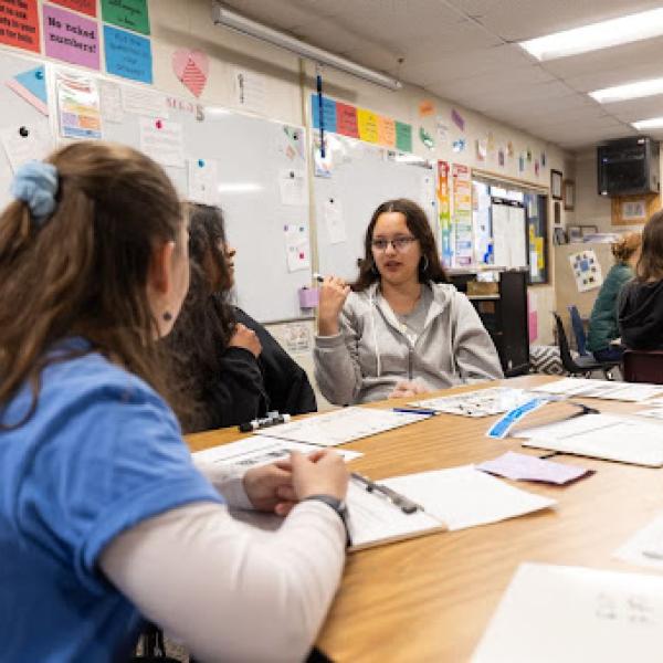 Group of people engaged in discussion while in a colorful classroom